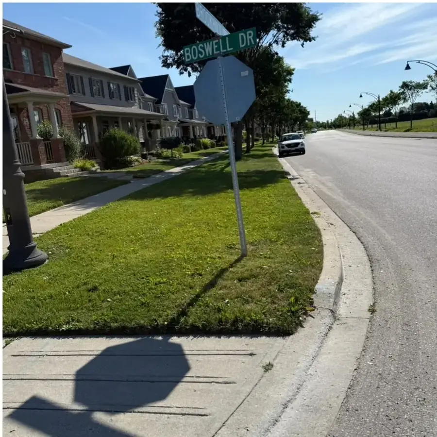 Corner-lot boulevard grass strip cut clean beside the road and sidewalk