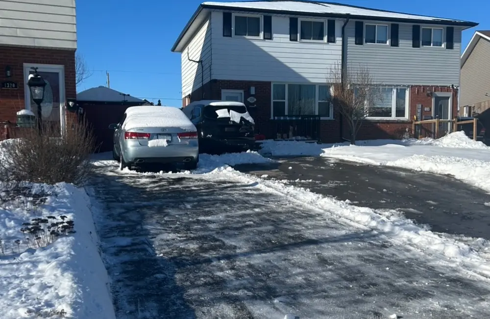 Driveway cleared of snow down to pavement between snowbanks