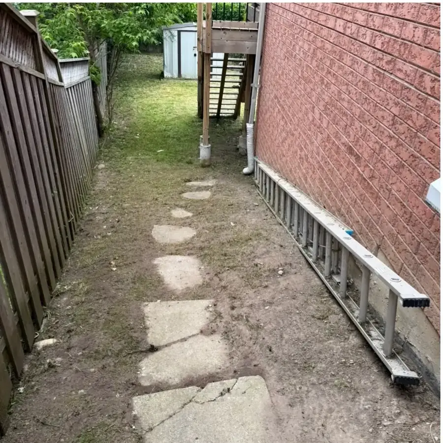 Stone side path cleared of overgrowth beside a brick house