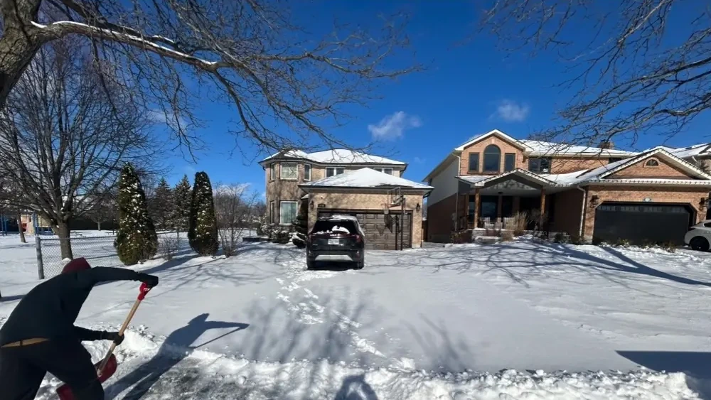 Driveway buried in deep snow with the owner shovelling